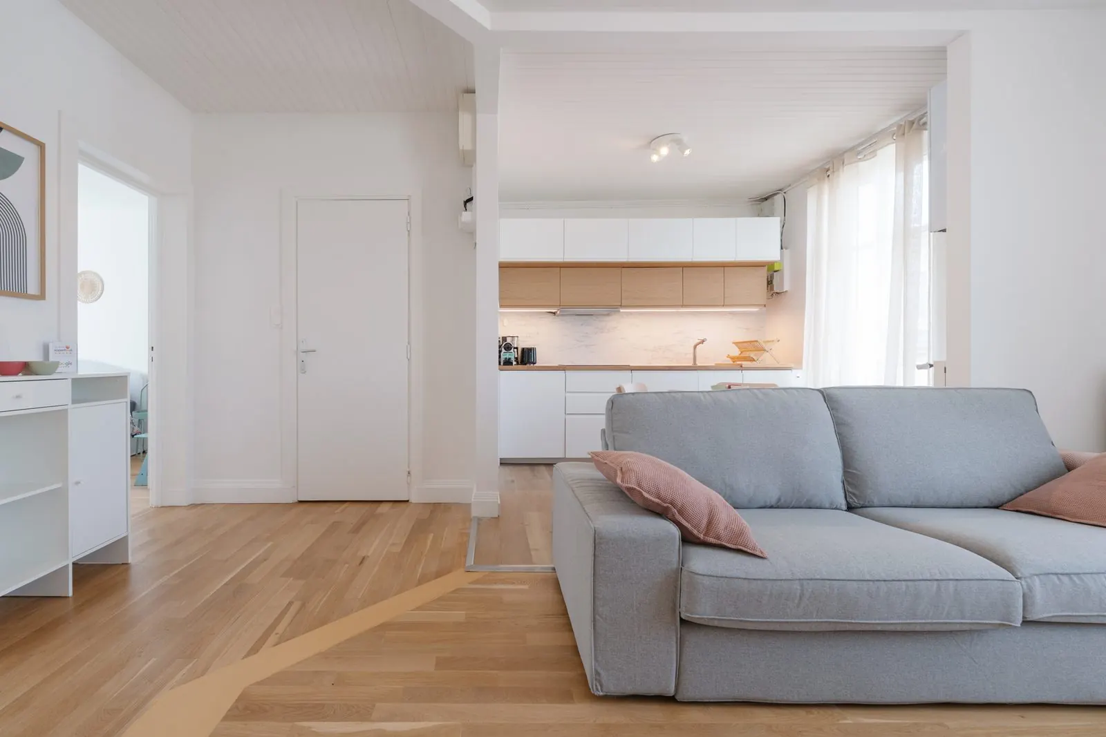 Artemis, furnished apartment, Nancy: living room with grey sofa, kitchen in the background