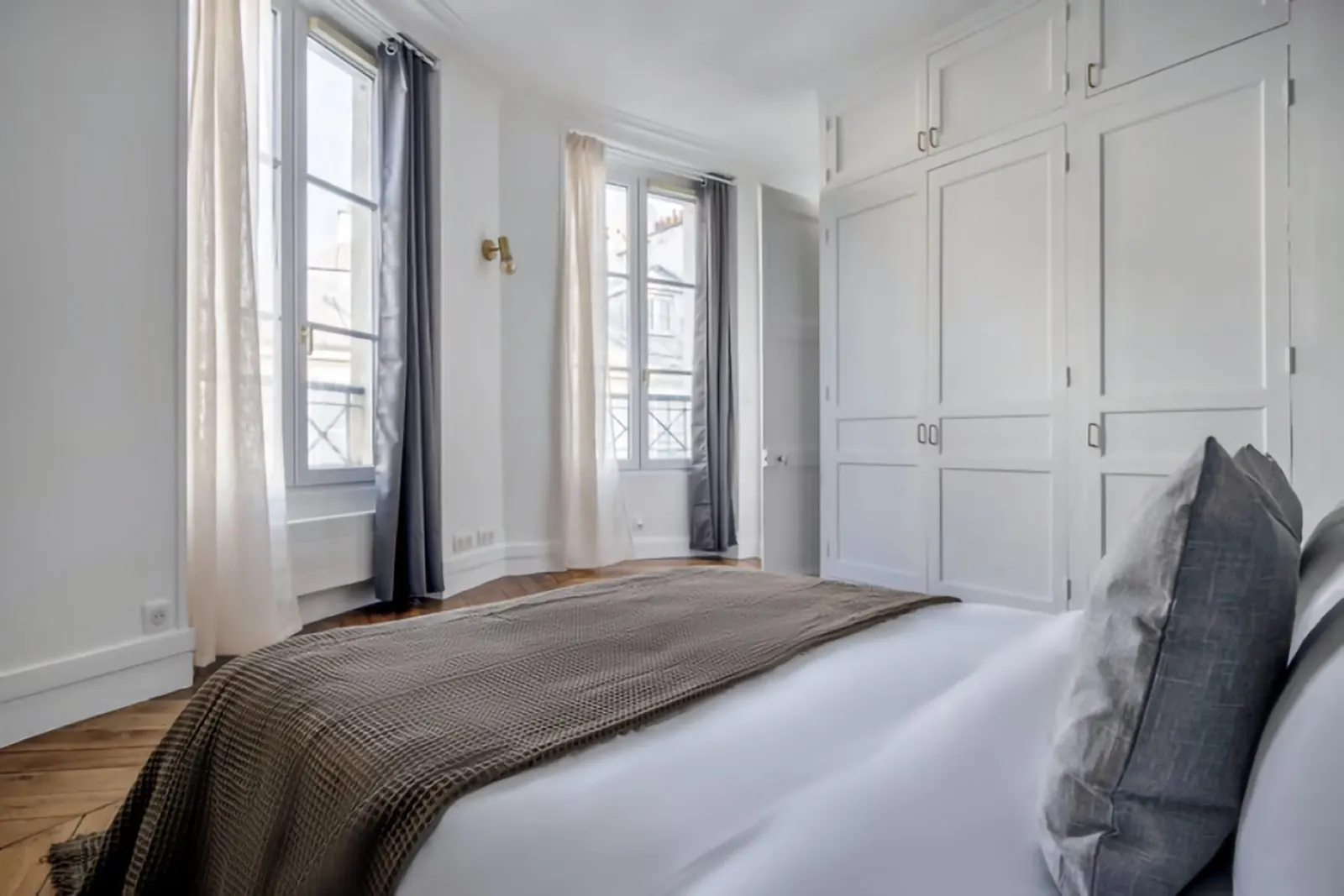 Le Bijou, furnished apartment, Paris 8th: bedroom with grey throw and fitted wardrobes