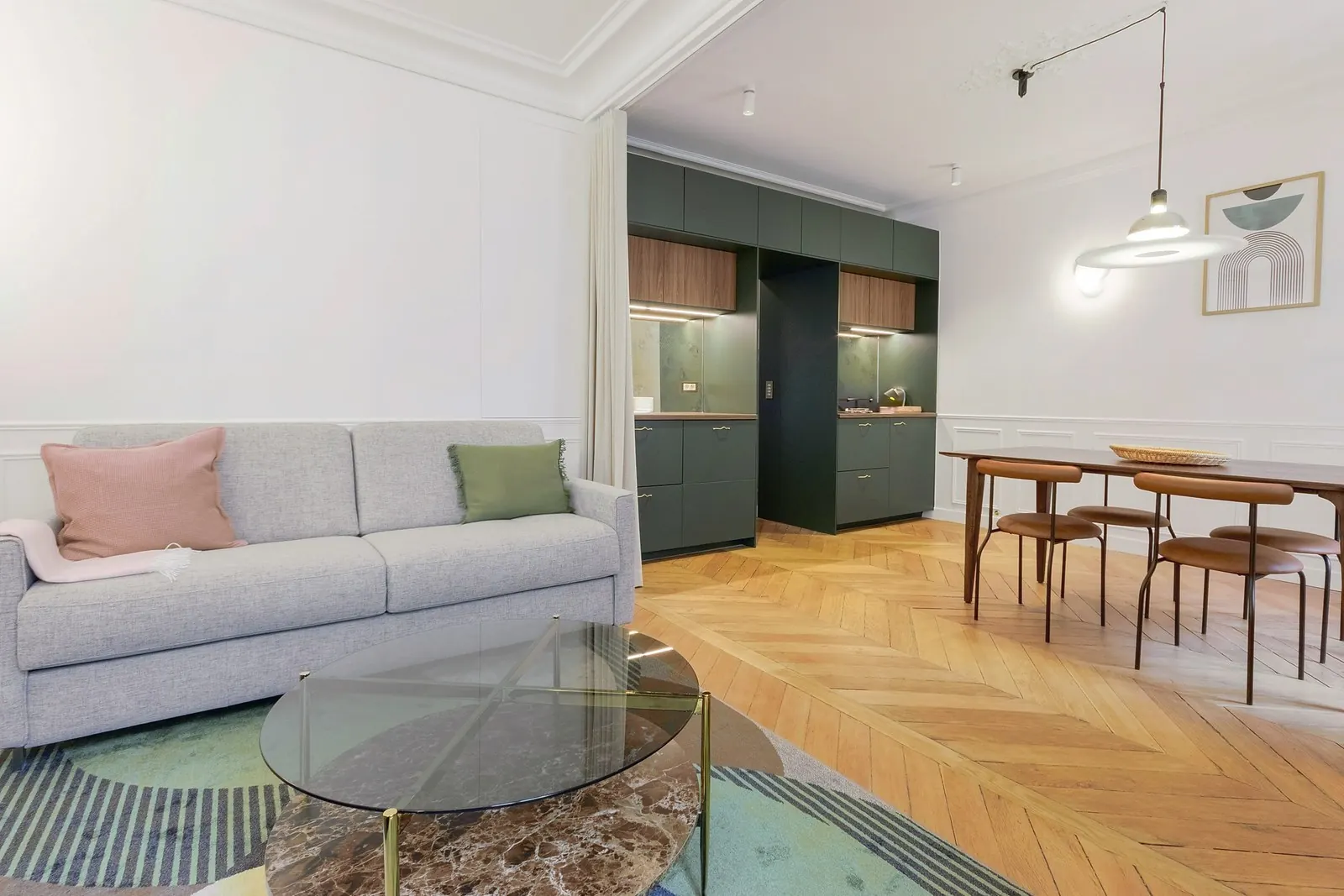 Le Gustave, furnished apartment, Paris 7th: the living room with its grey sofa and dark green kitchen